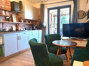 A kitchen with white cabinets, a wooden countertop, and a green upholstered chair. - Pokoje Gościnne Magnolia (Serock)