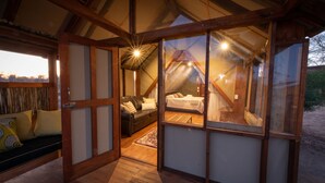 Ein gemütliches, helles Schlafzimmer im Dachgeschoss mit Holzbalkendecke, einer bequemen Couch und einem Bett.