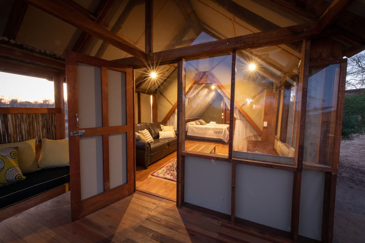 Un dormitorio cálido y luminoso en el ático, con techo de madera, un sofá cómodo y una cama.