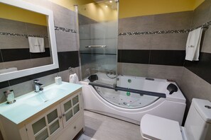 A modern bathroom with a glass-enclosed shower, a freestanding bathtub, and a toilet.