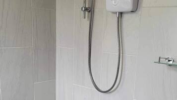 A modern bathroom with a shower, toilet, and a control panel on the wall.