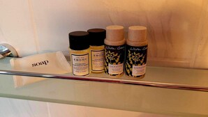 Ein Badezimmerschrank mit vier Flaschen Haar- und Duschgel sowie Seife und einem Handtuch.