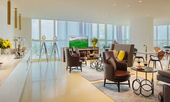 Amplia sala de estar con televisor grande, asientos cómodos y vistas a la ciudad.
