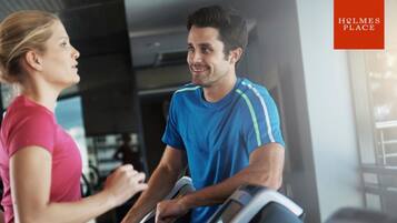 A gym interior with exercise equipment and a person using a treadmill.