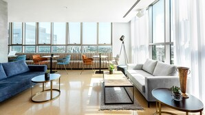 Amplia sala de estar con un sofá, sillones, una mesita de centro y un ventanal con vistas a la ciudad.