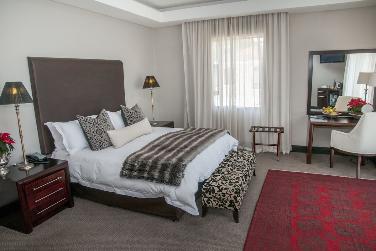 A hotel room with a large bed, bedside tables, a desk, and a chair.