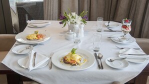 A dining table set with plates, cutlery, and a glass of dessert. - The Mount Knysna (Knysna)