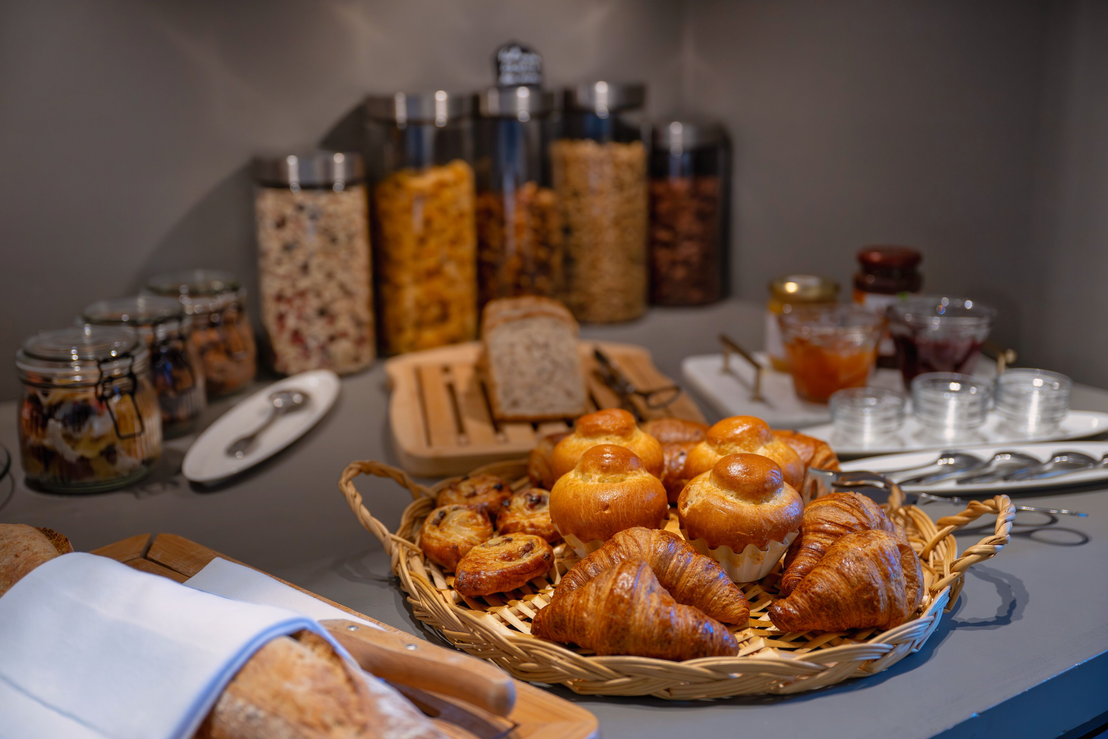 Een ontbijtbuffet met diverse broden, gebak en toevoegingen.