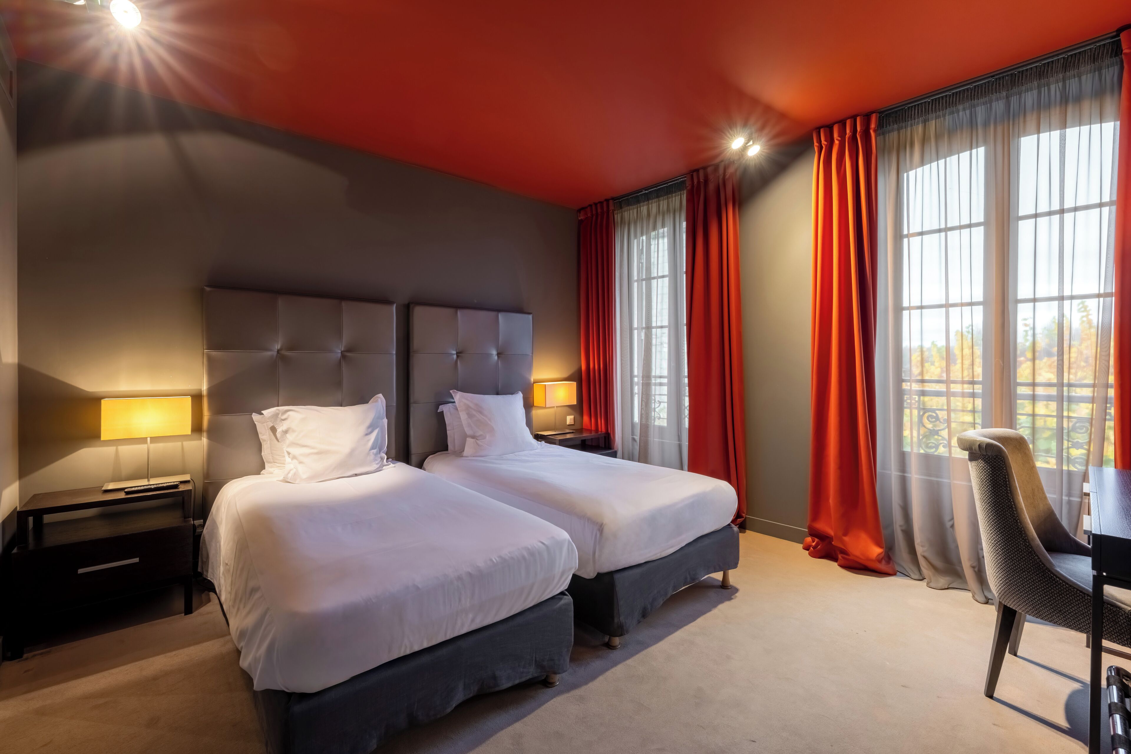 A hotel room with two beds, a desk, and a chair.
