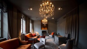 A modern living room with a fireplace, comfortable seating, and a chandelier. - Hotel Ligaro - Jarnac (Jarnac)