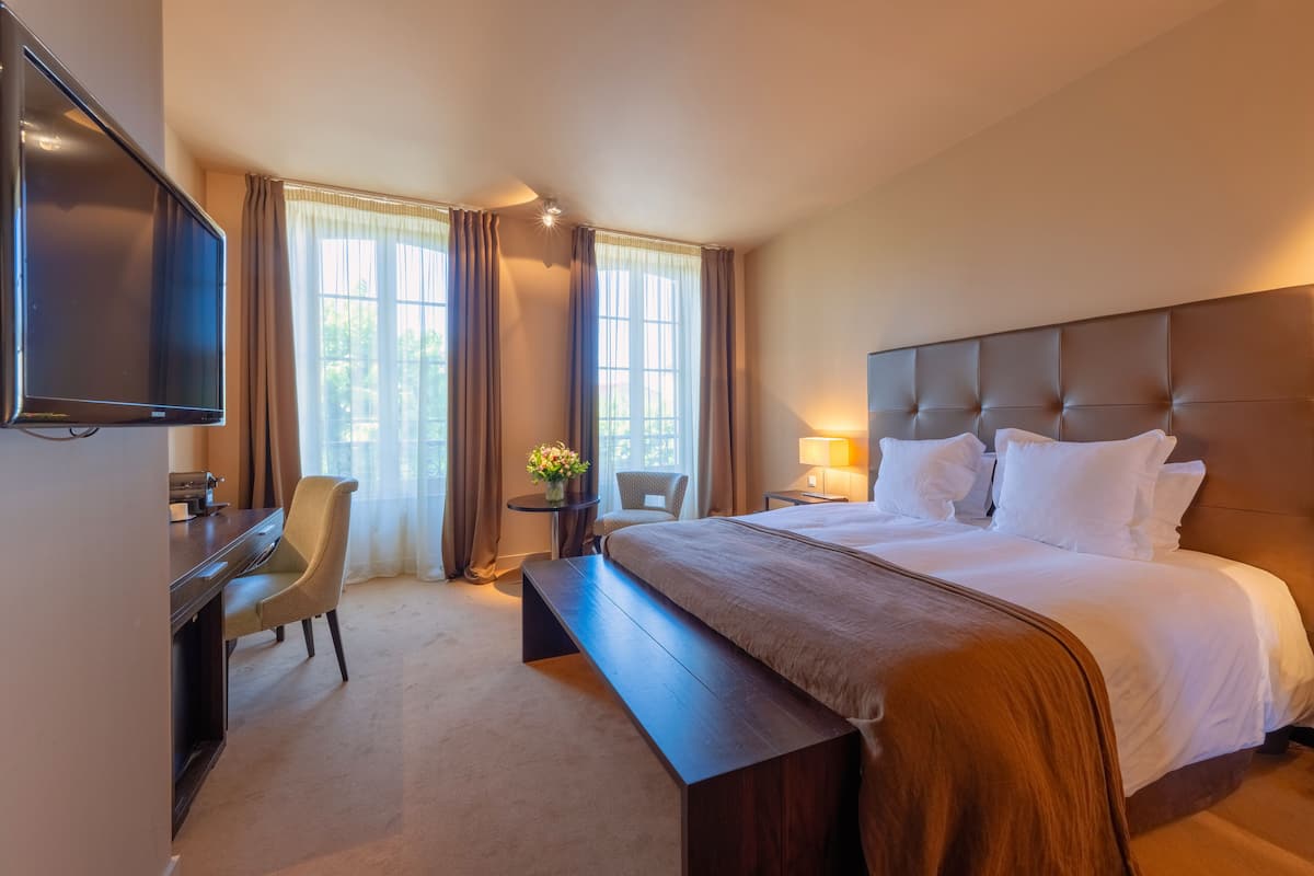 Habitación de hotel con una cama grande, un escritorio, una silla y un televisor.