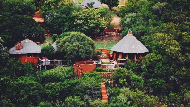 A resort with thatched-roof cottages surrounded by dense greenery. - Leshiba Wilderness (Louis Trichardt)