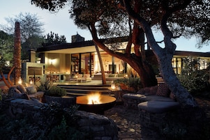 Una casa moderna con una fogata, asientos al aire libre y un sendero de piedra.