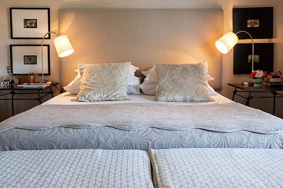 A neatly made bed with a patterned bedspread and pillows, two bedside lamps, and framed pictures on the wall.