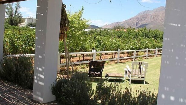 Un'area esterna coperta con un recinto bianco, due sedie e una struttura a pergola.