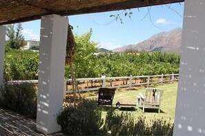 Ein überdachter Außenbereich mit weißem Zaun, zwei Stühlen und einer Pergola.