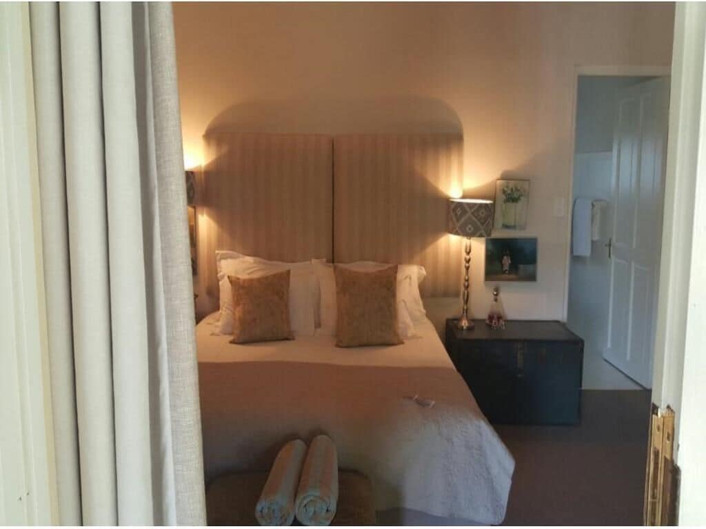 A bedroom with a large bed, a nightstand, a lamp, and a door.