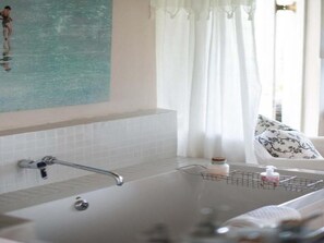 A bathroom with a bathtub, a shower, a towel rack, and a window with curtains. - The Vineyard Country House (Montagu)