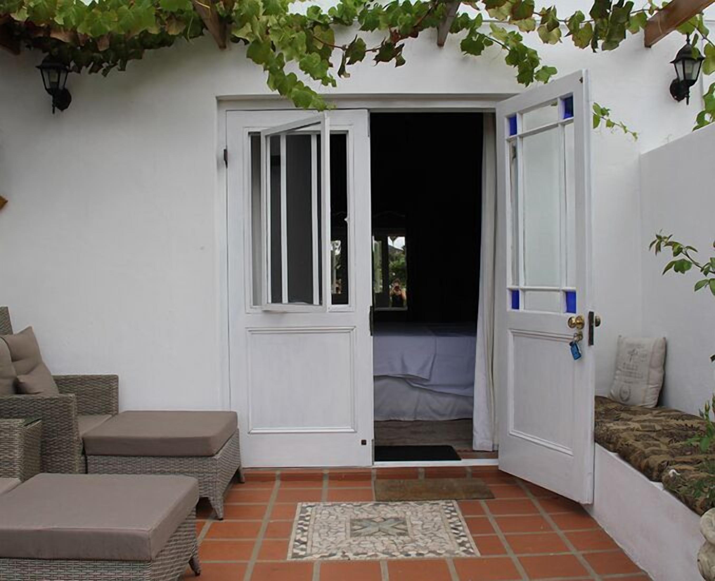 A white door with a window, a wicker sofa, and a patterned rug on a tiled patio.