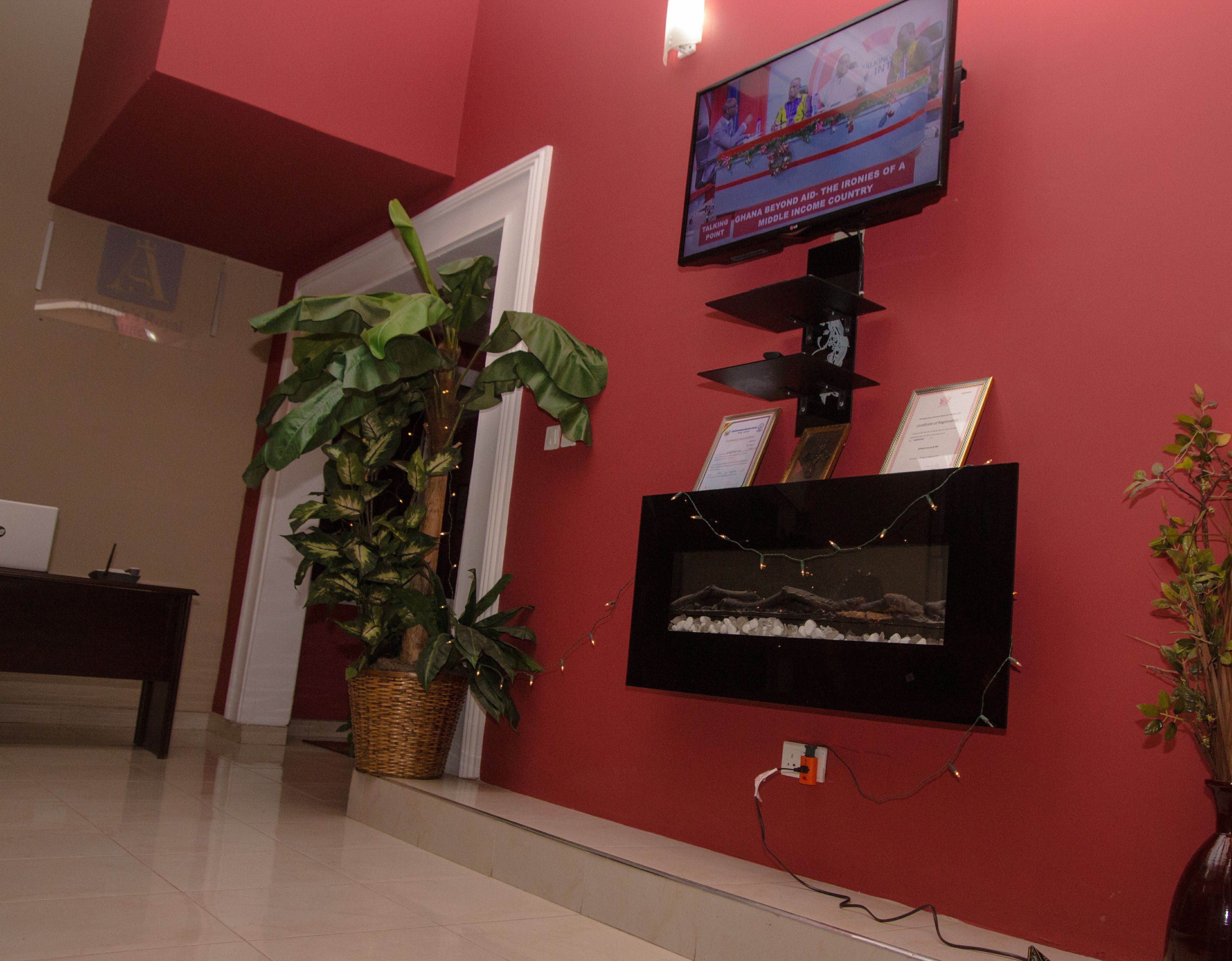 A reception area with a television mounted on the wall, a fish tank, and a potted plant.