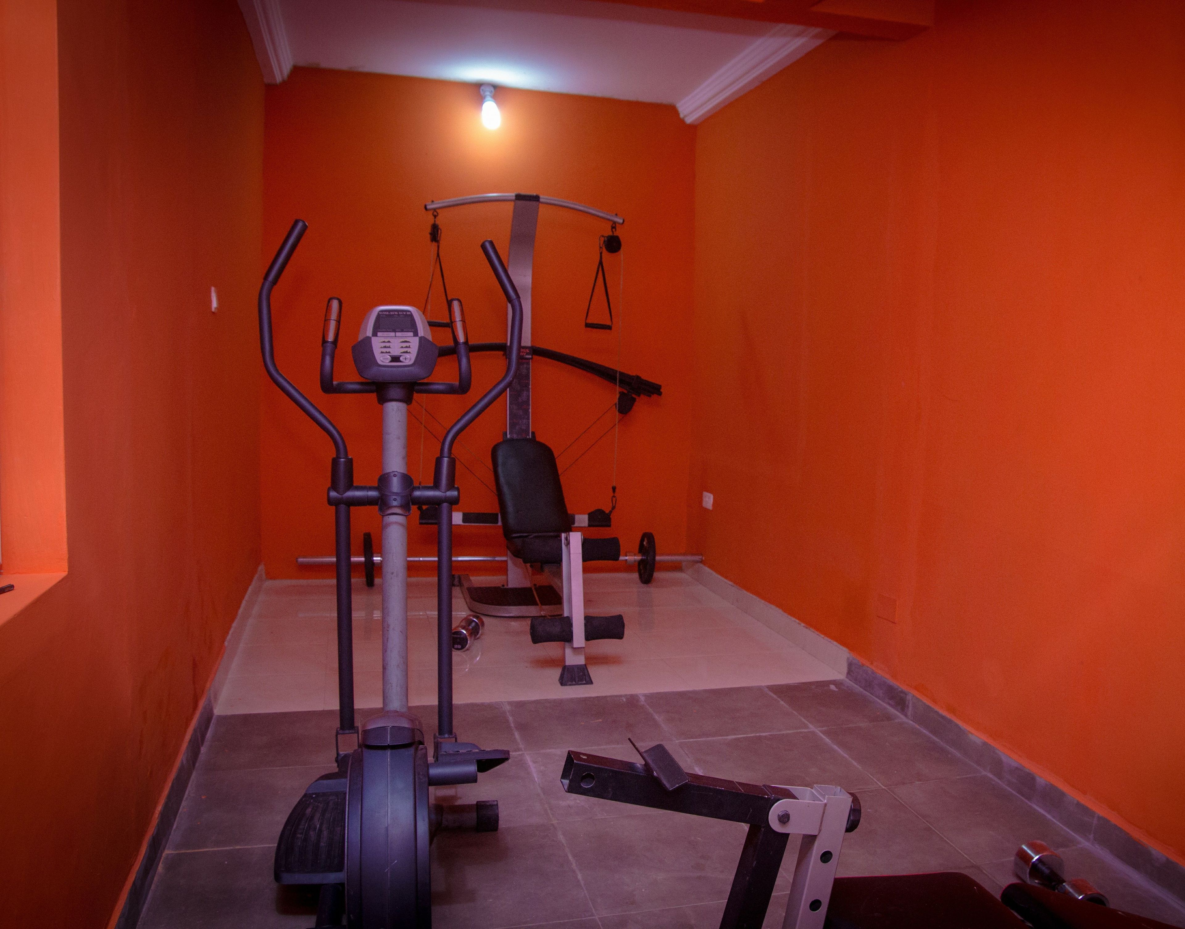 Et fitnesscenter med træningsudstyr, herunder en crosstrainer, bænkpres og en squat-rack.