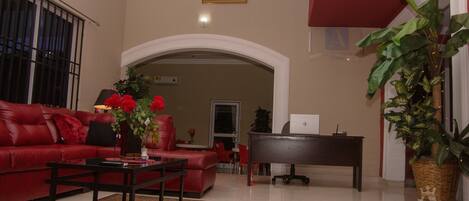 Amplia sala de estar con un sofá rojo, una mesa de centro y un piano.