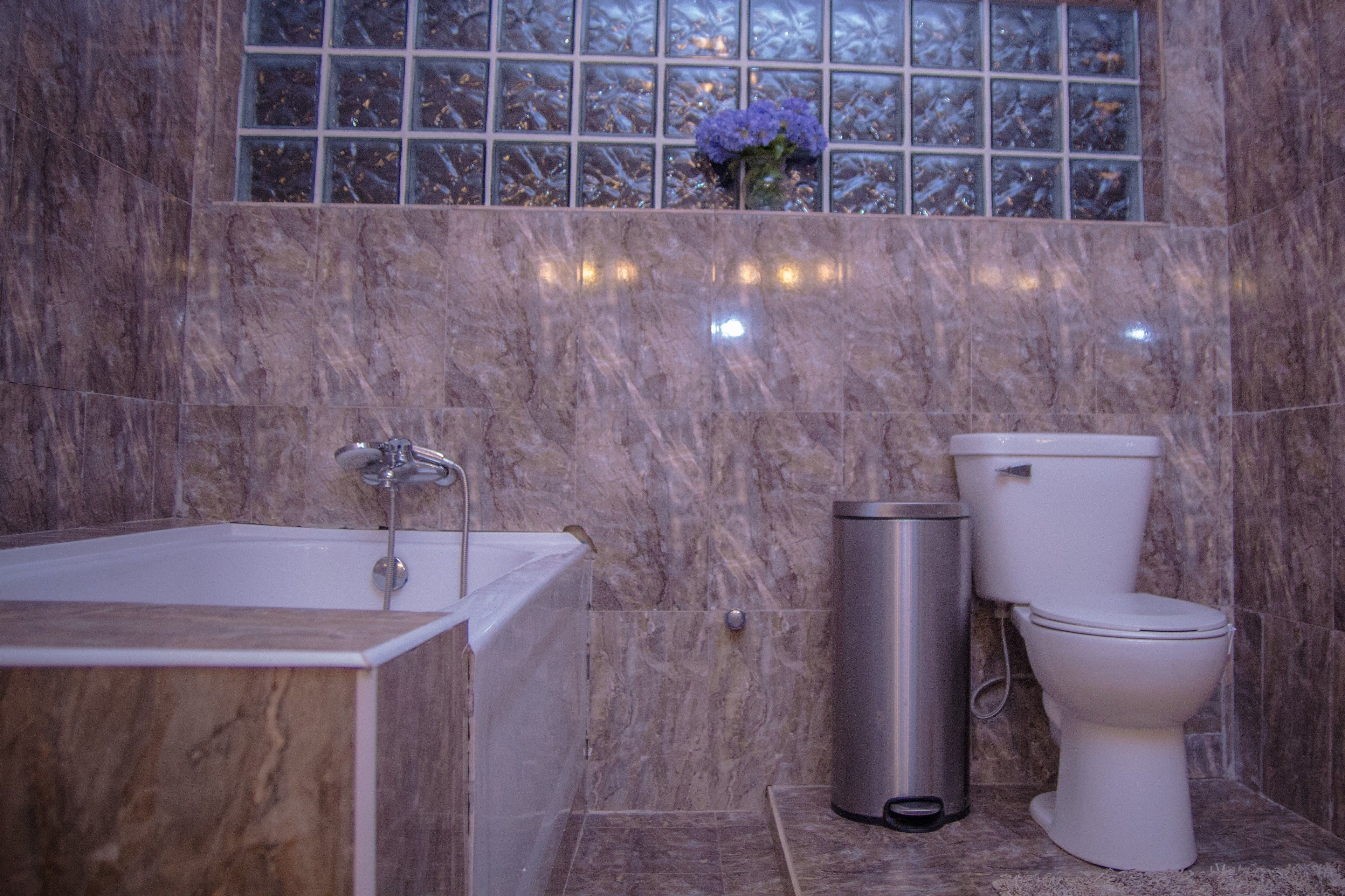 Un baño con bañera, inodoro y cubo de basura.