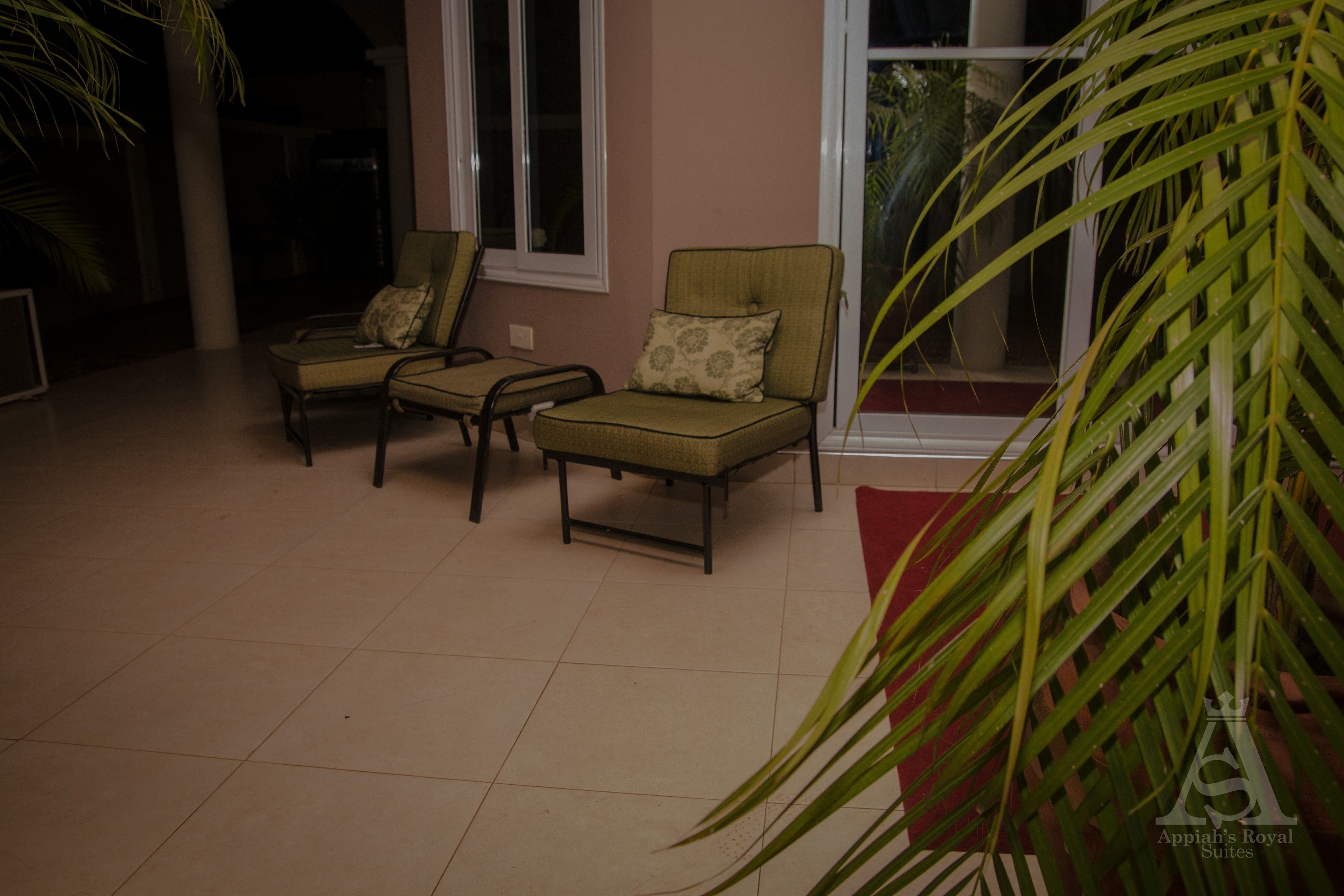 A room with two armchairs and a table, a large window, and a potted plant.