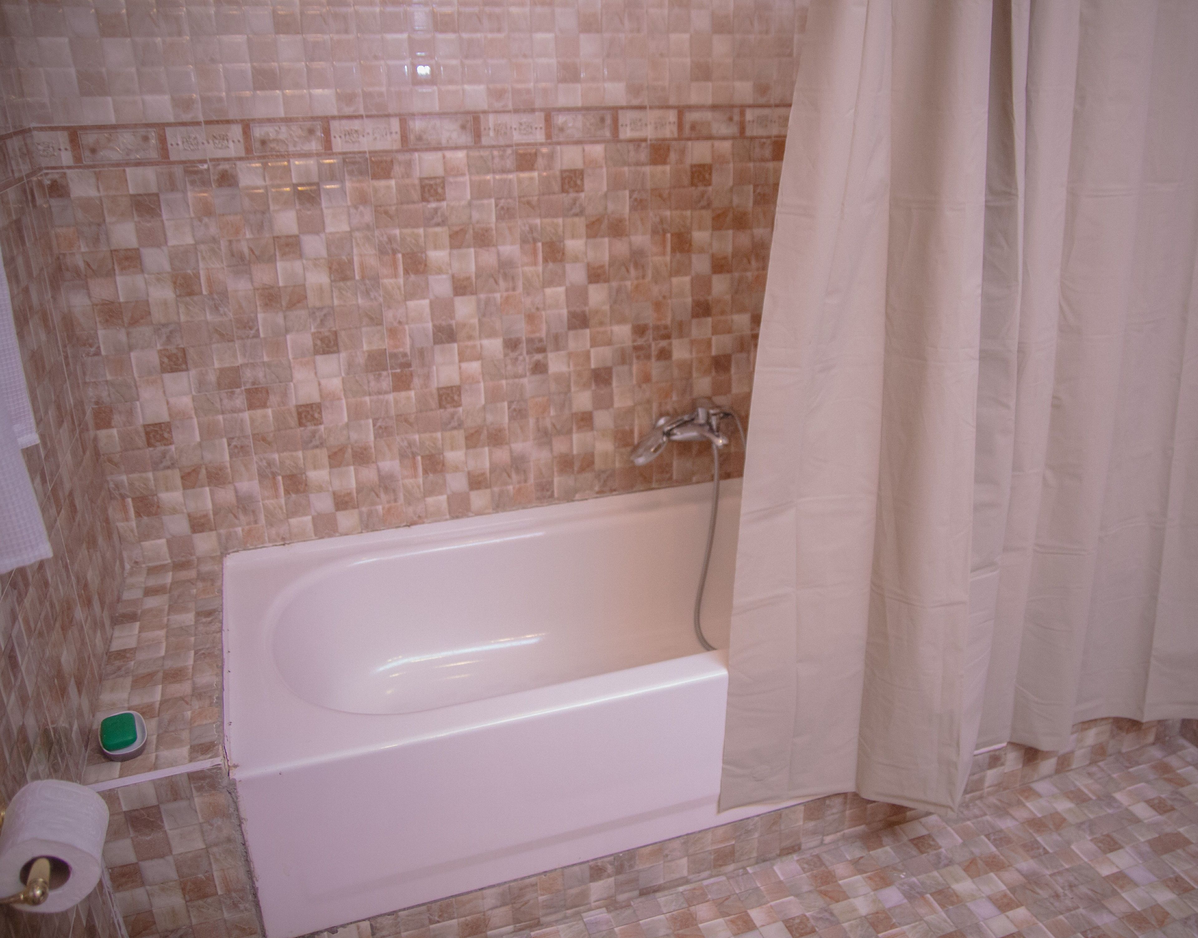 A bathroom with a bathtub, tiled walls, and a shower curtain.