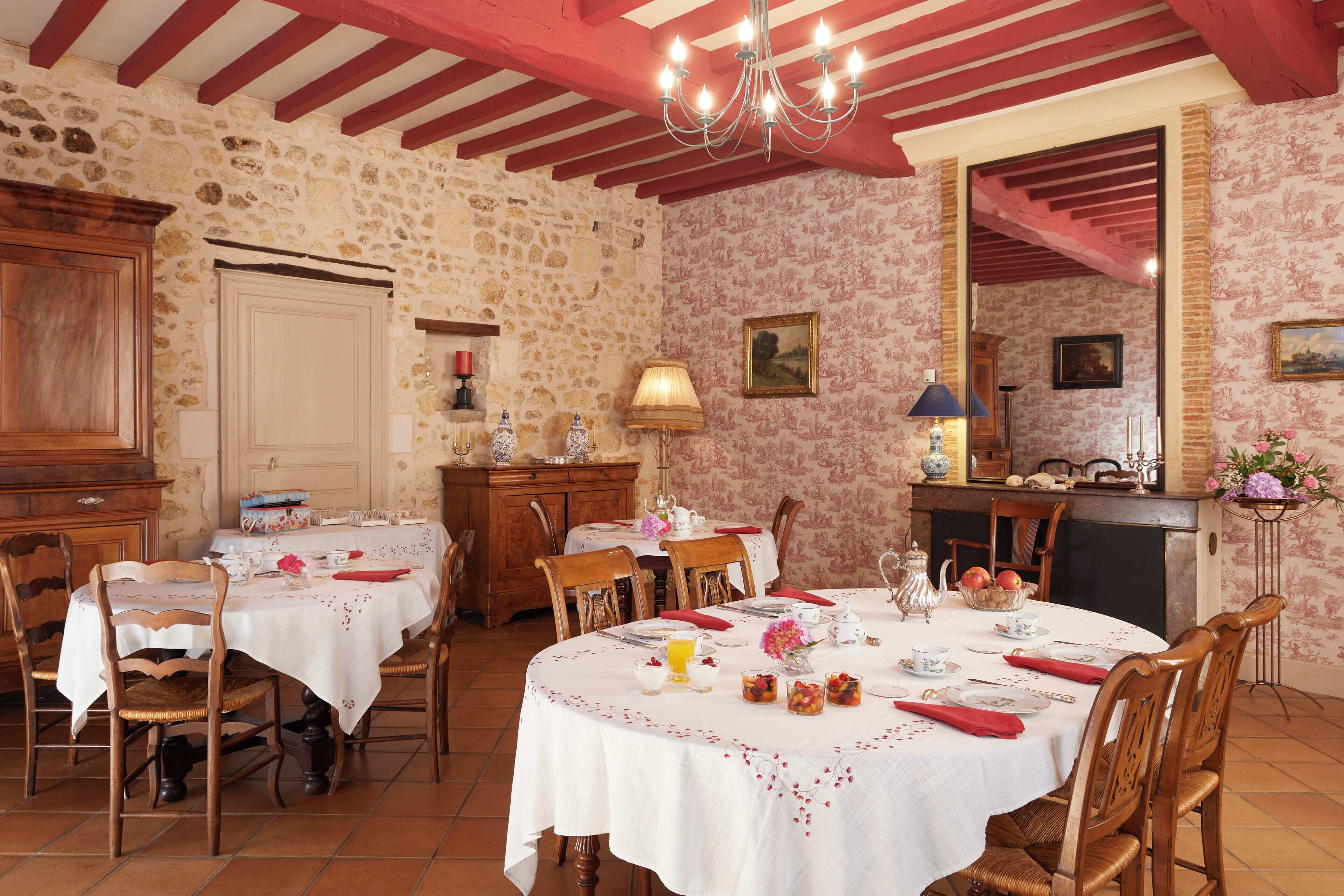 Un comedor con paredes de piedra, muebles de madera y una lámpara de candelabro.