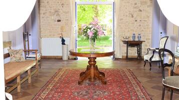 Une pièce avec une table en bois, un tapis rouge à motifs, un banc et une chaise.