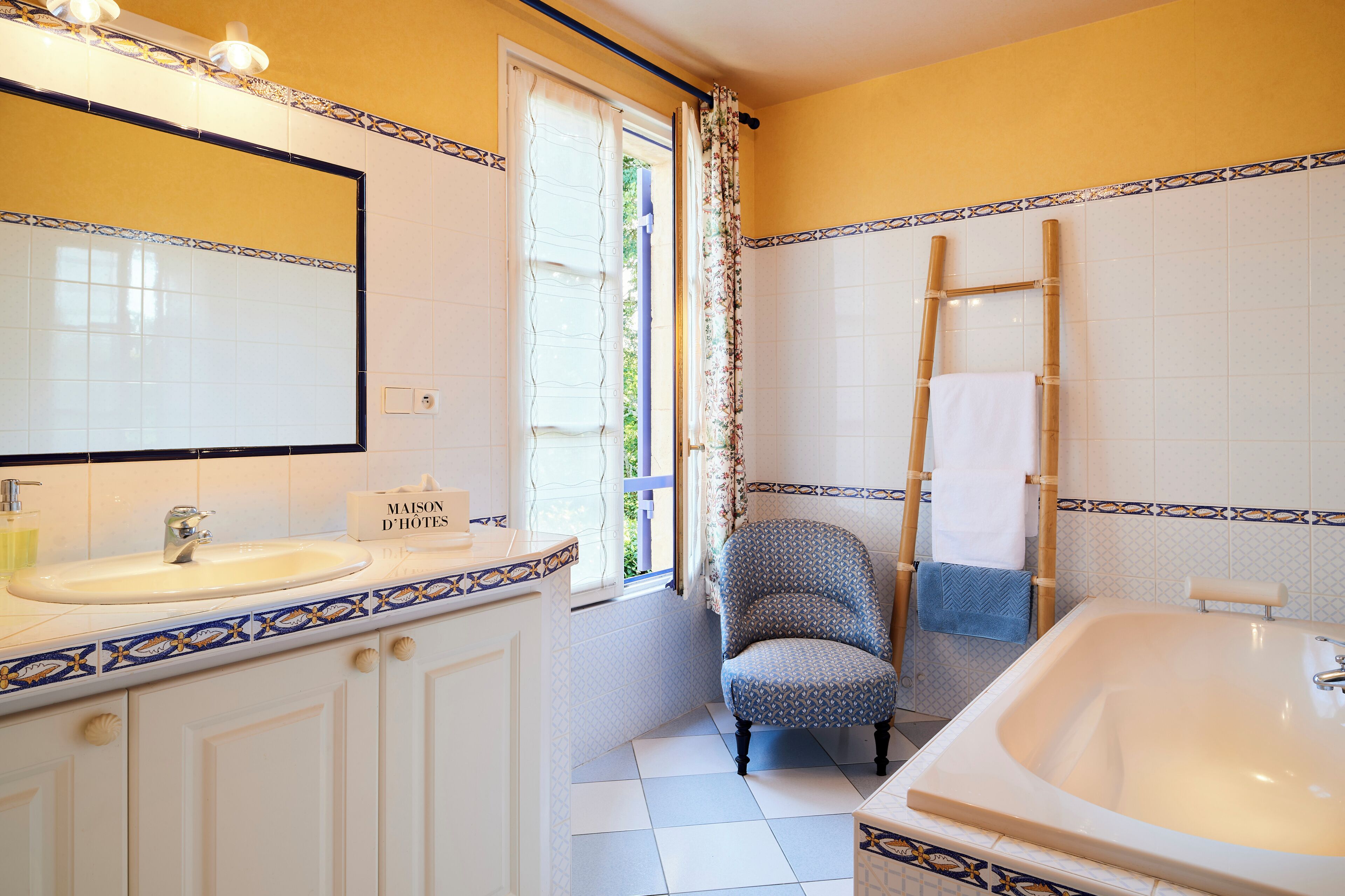 A bathroom with a large mirror, a sink, a bathtub, and a chair.
