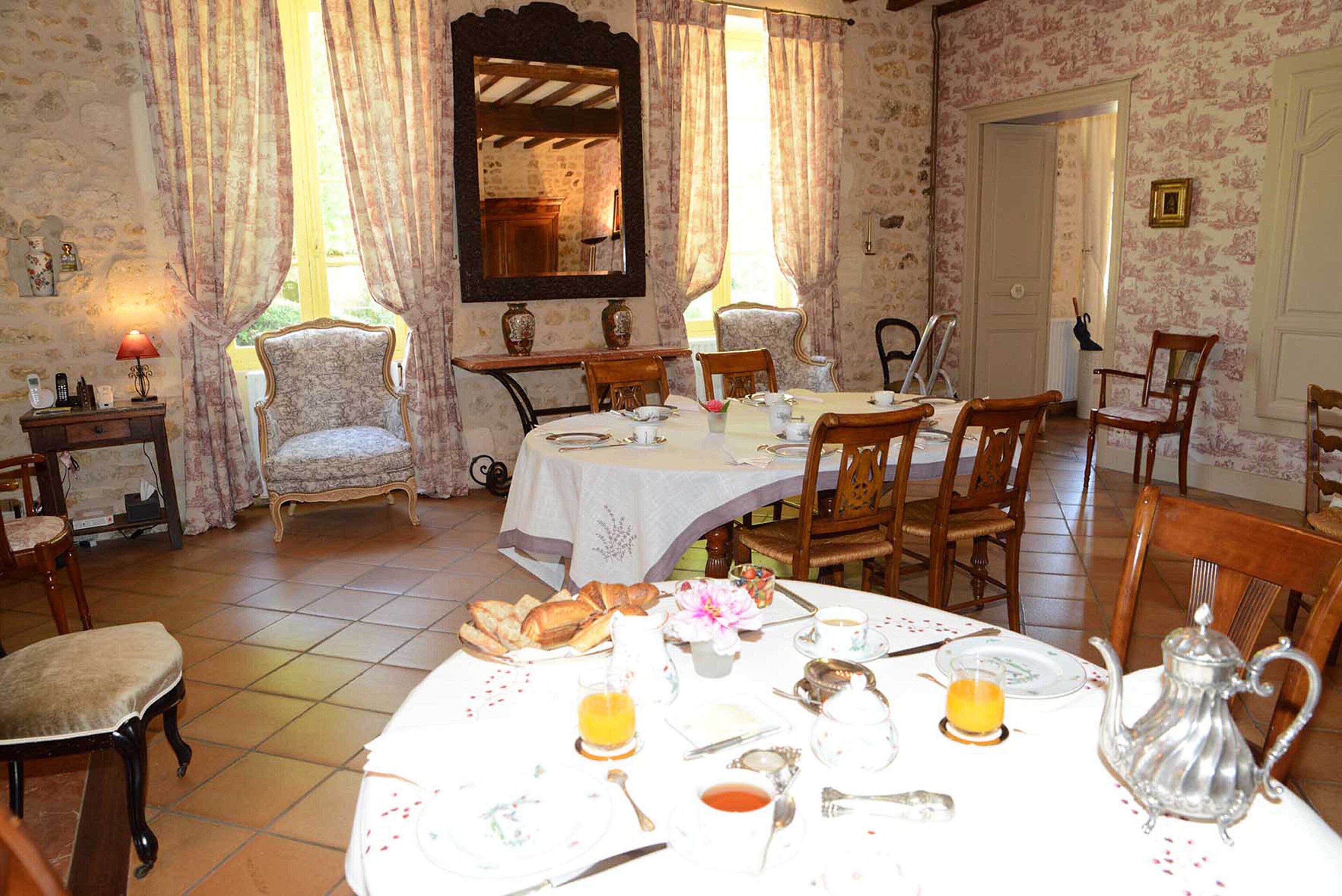 A dining room with a round table set for breakfast, including bread, eggs, and beverages.
