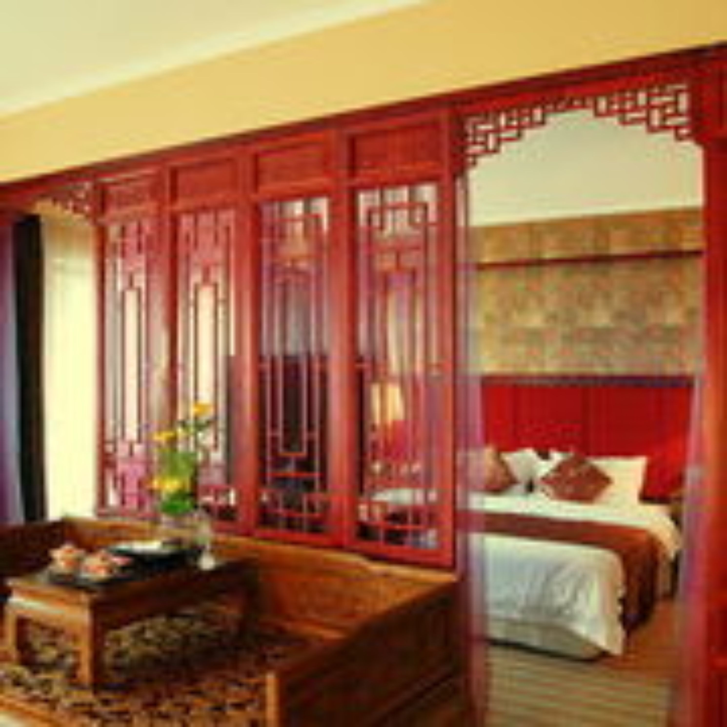 A traditional room with a bed, a wooden sofa, and a decorative screen.