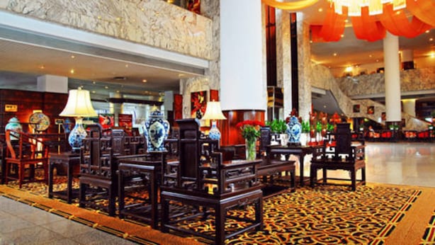 A lobby with traditional furniture, a patterned carpet, and a marble wall. - Le Garden (Xi'an)