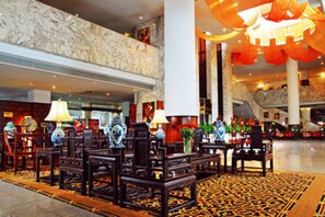 A lobby with traditional furniture, a patterned carpet, and a marble wall.