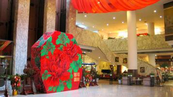 A spacious indoor area with a large decorative floral structure, marble columns, and an escalator.