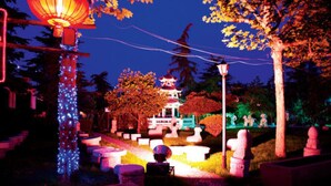 A traditional pagoda with a lantern, surrounded by stone lanterns and pathways. - Le Garden (Xi'an)