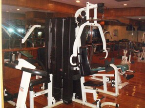 Een sportschool met diverse trainingsapparaten, waaronder een bankdrukpers en een rek voor squats.
