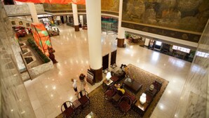 A spacious lobby with marble flooring, a central seating area, and a large mural on the wall. - Le Garden (Xi'an)