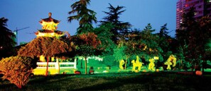 Een traditioneel pagode-gebouw met een terrasvormig dak, omgeven door bomen en een modern gebouw op de achtergrond.