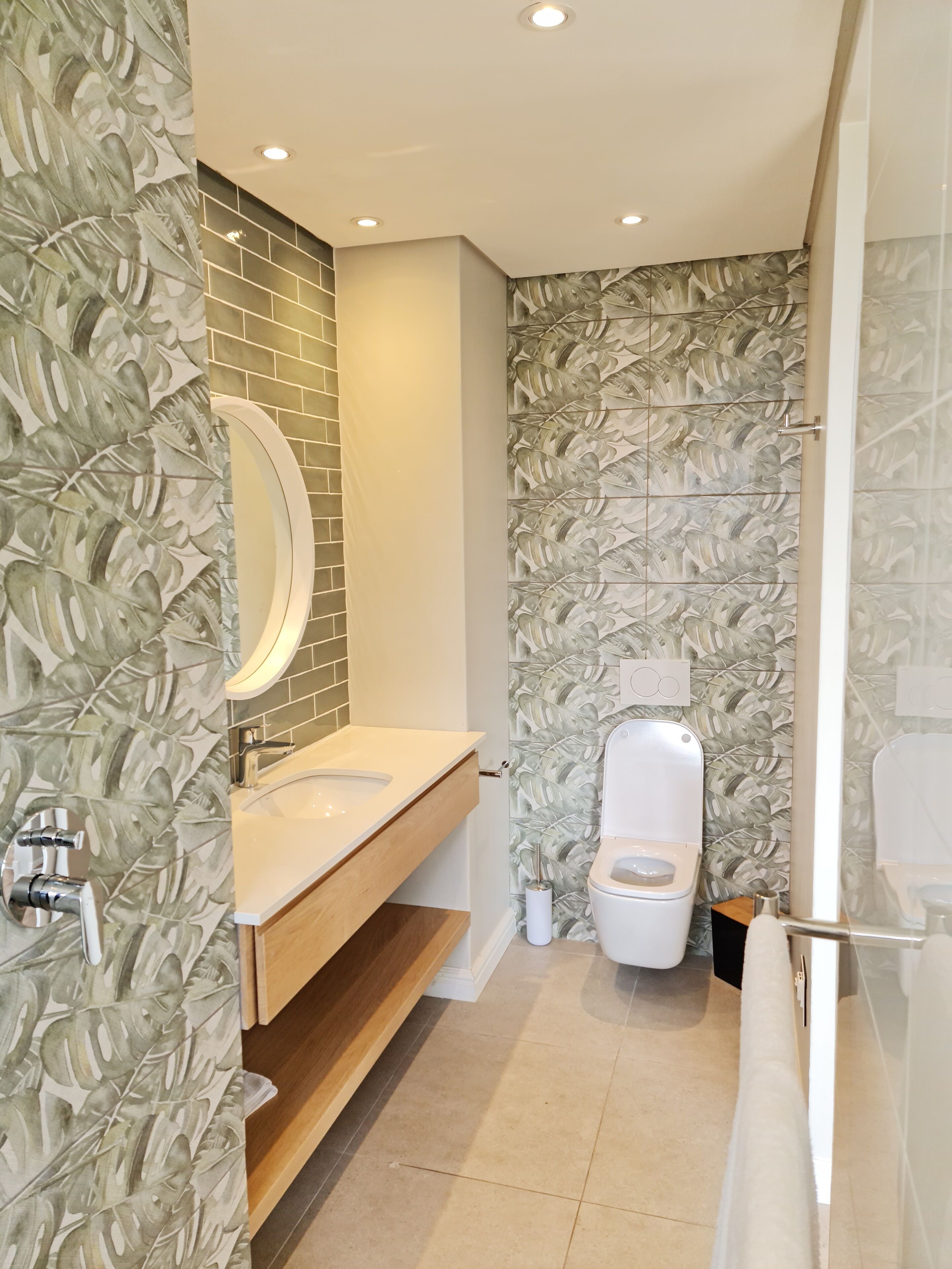 Un baño moderno con tocador de madera, inodoro y zona de ducha.