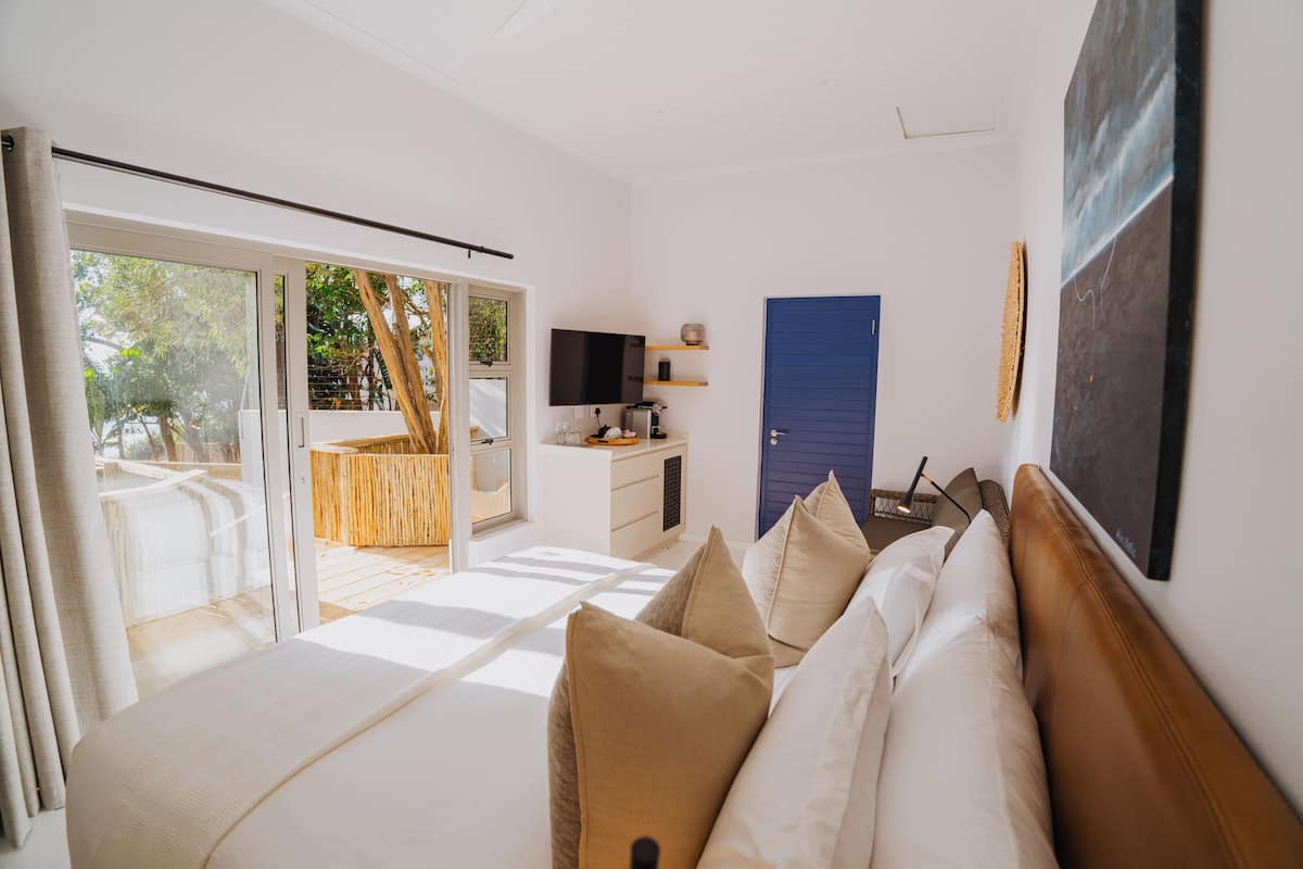 Quarto moderno com cama, televisão, escrivaninha e porta.