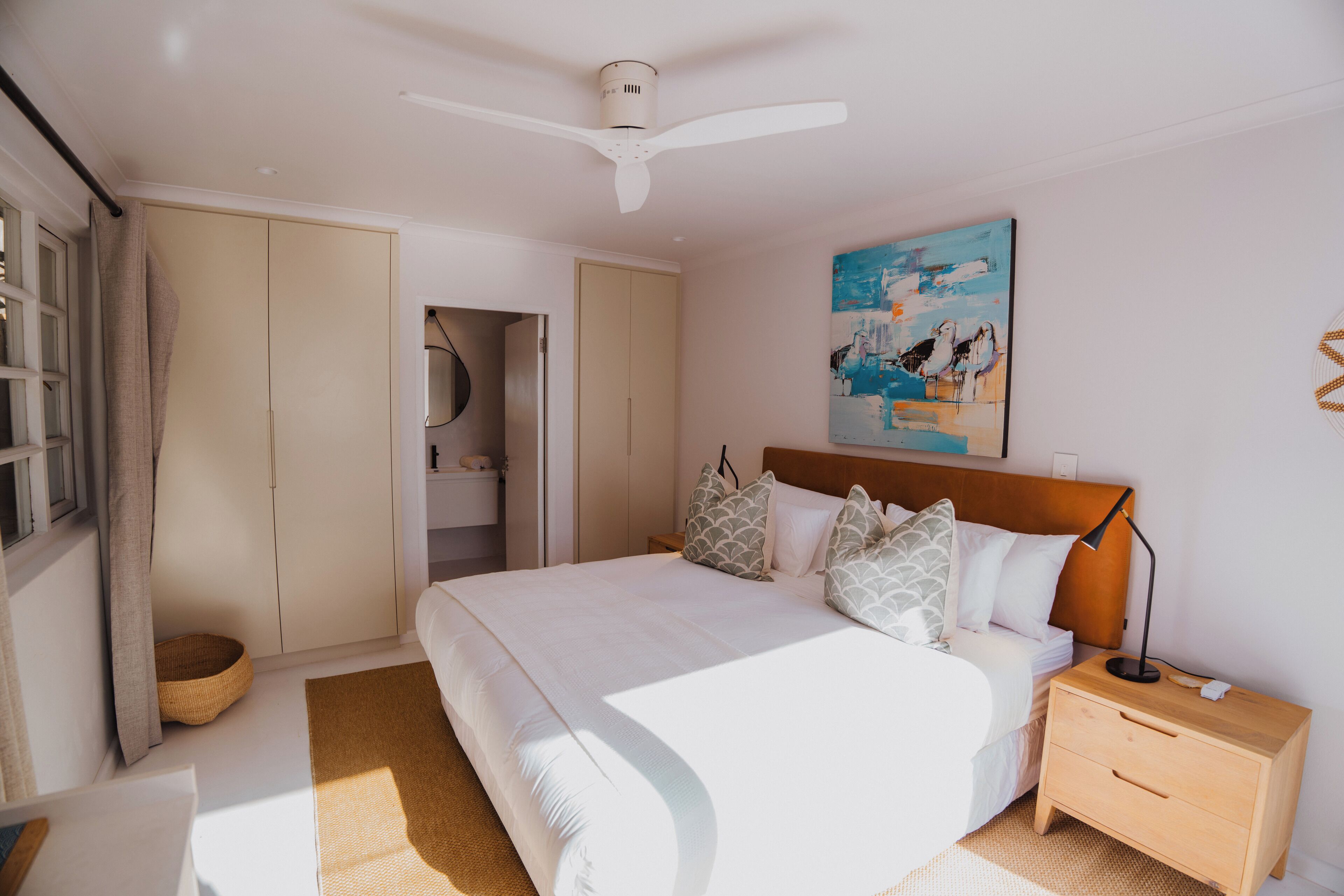 Un dormitorio con cama, mesita de noche y ventilador de techo.