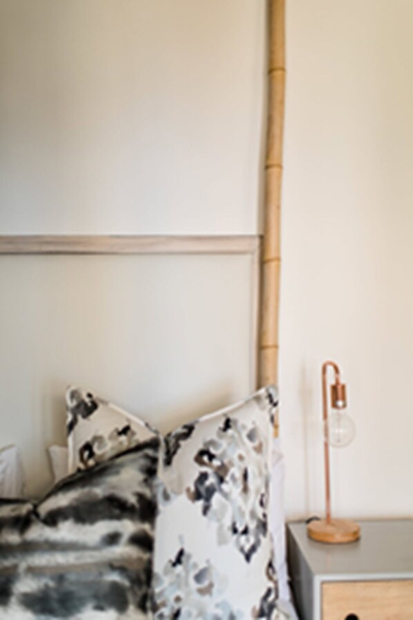 A bedroom with a bed, pillows, a bedside table, and a lamp. - The Bungalow (Plettenberg Bay)