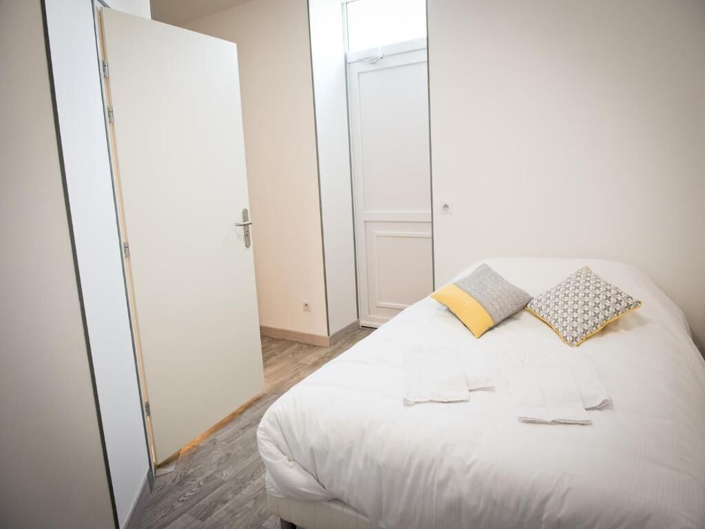 Quarto com cama, almofadas e porta.