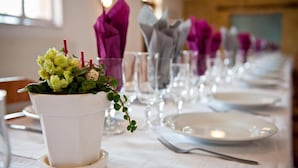 Mesa lista para comer, con mantel blanco, copas de cristal transparente y servilletas moradas.