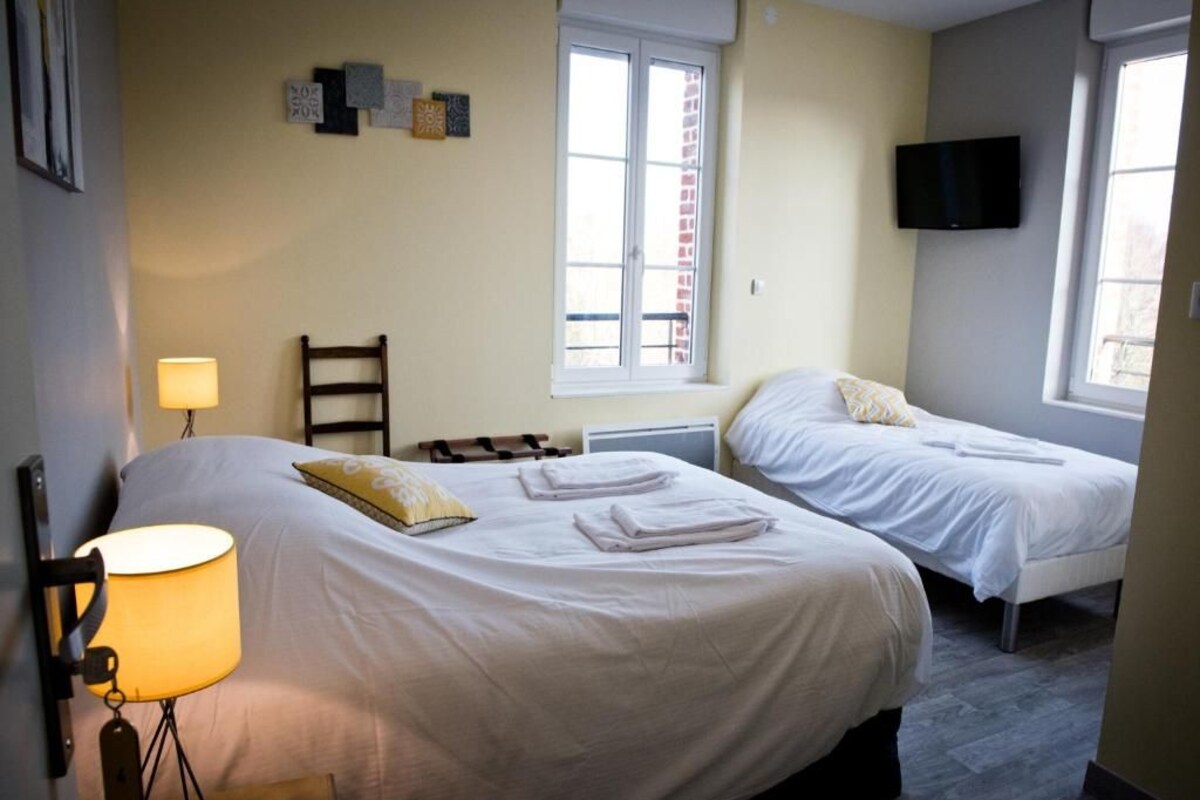 Habitación de hotel con dos camas, un televisor, una lámpara y una ventana.