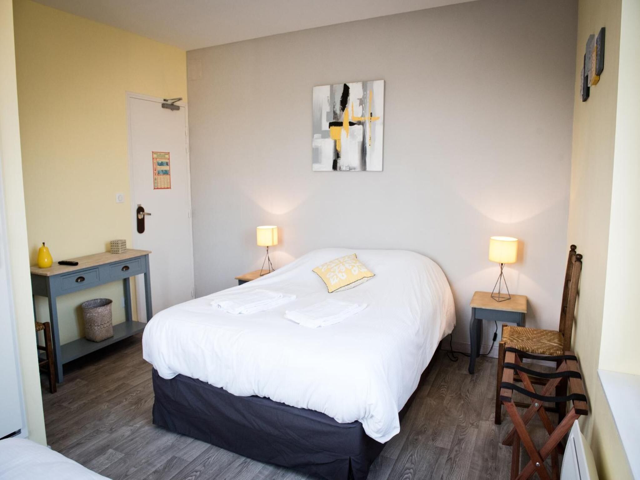 A bedroom with a bed, bedside tables, a chair, and a wall-mounted artwork.
