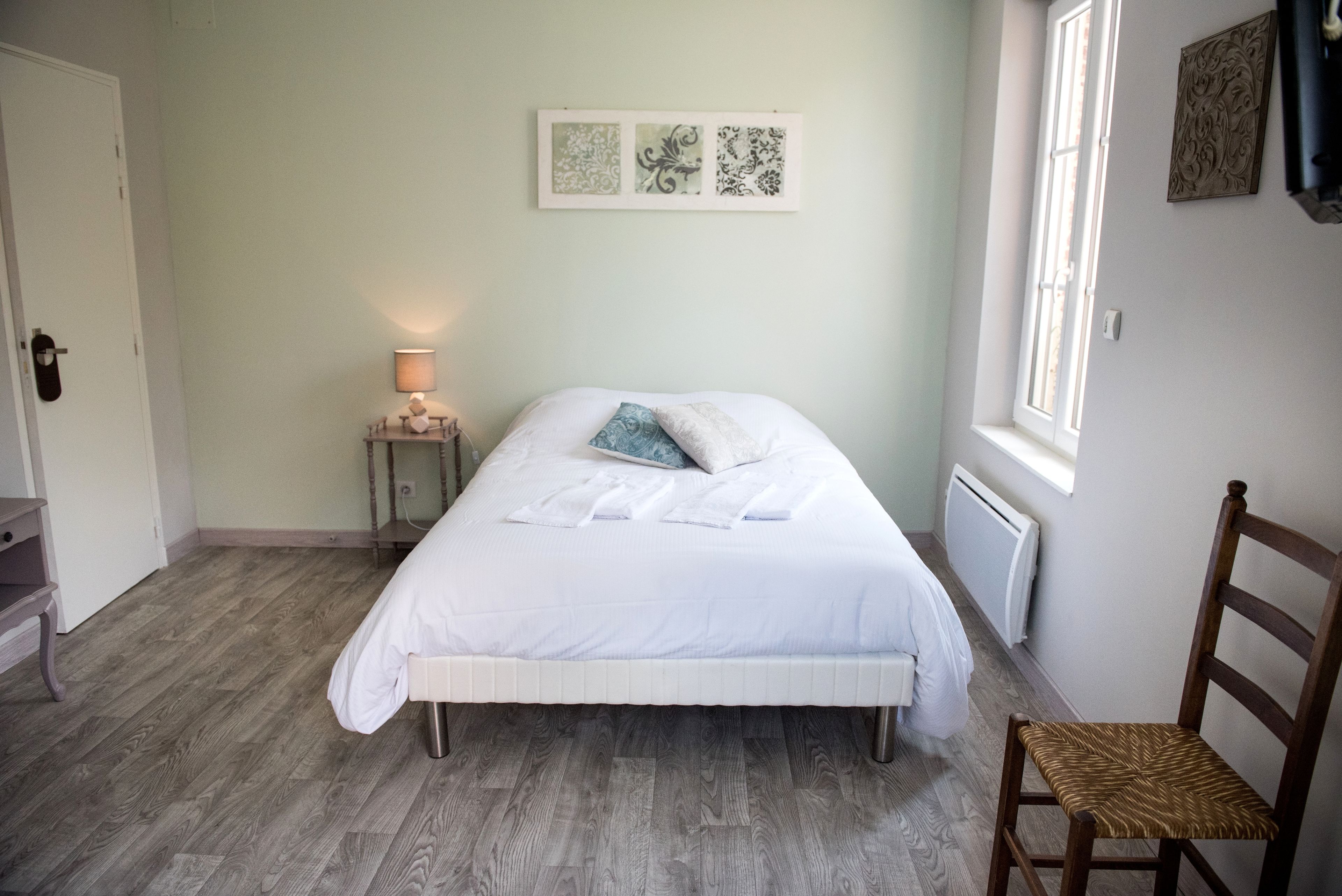 A bedroom with a bed, a nightstand, a chair, and a window.